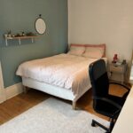 Private student bedroom with double bed, desk, chair and large mirror in a Lyon host family home.