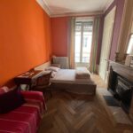 Spacious student bedroom with queen-size bed, desk, sofa and large window in a host family apartment in central Lyon.