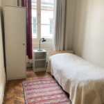Bright private student bedroom in a homestay in central Lyon, with single bed, desk area, storage and large window.