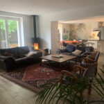 Cosy family living room with sofas, fireplace and open-plan kitchen in a Lyon homestay.