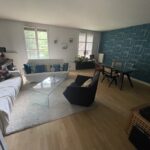 Bright living and dining room with sofas, dining table and large windows in a host family home in Lyon.