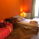 Bright student bedroom with queen-size bed, desk and sofa in a host family apartment in central Lyon.