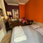 Spacious student bedroom with queen-size bed, sofa and study desk in a host family apartment in central Lyon.