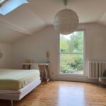 Spacious and bright guest bedroom with double bed, desk and garden view in a family home near Lyon.
