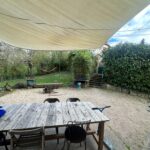 Private garden with outdoor dining table and covered terrace at a host family home in Tassin-la-Demi-Lune near Lyon.