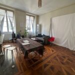 Spacious living room with traditional wooden flooring and large windows in central Lyon.