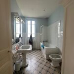 Bright family bathroom with bathtub, sink and large windows in a homestay near Lyon.