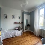 Bright single student bedroom with wooden floor, large window and study area in a homestay near Lyon.