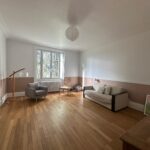 Large bright living room with wooden floors, sofa and armchairs in a host family home near Lyon.